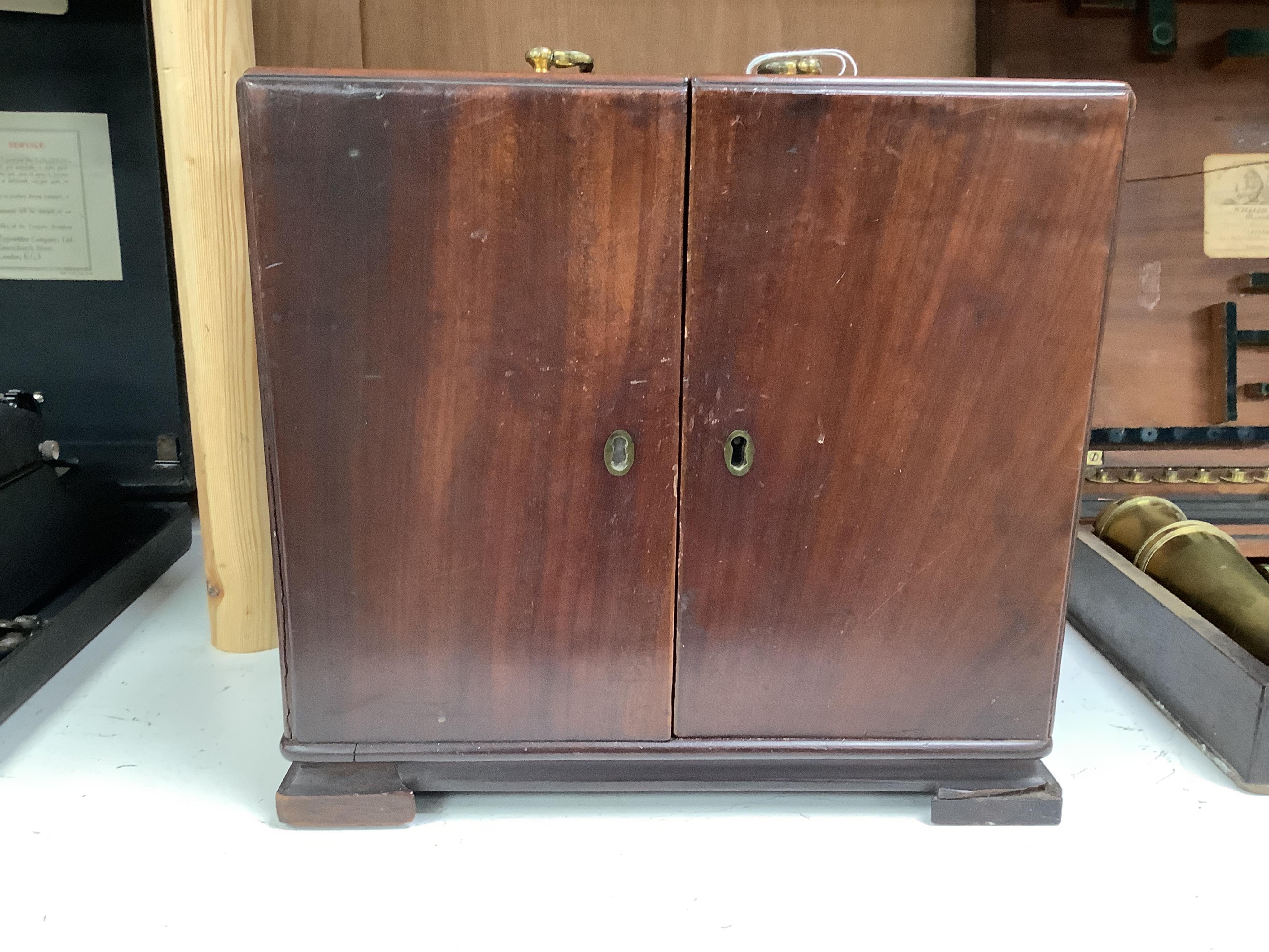 A 19th century mahogany apothecary cabinet, containing 20 bottles of various medicinal compounds and poisons, some sealed, all with paper labels, mainly for ‘C. Woollven, Operative & Dispensing Chemist, 108, High Street,